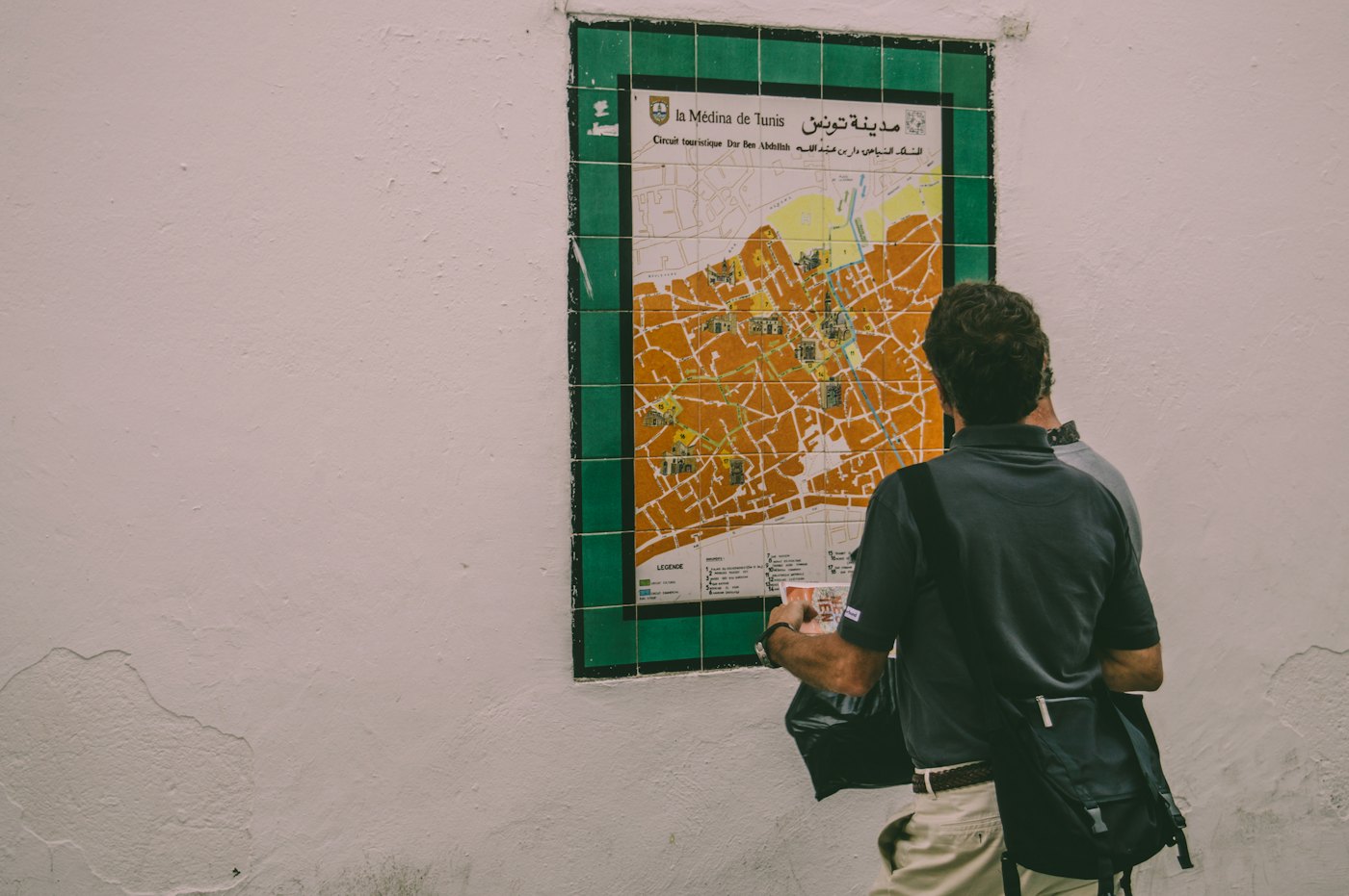 Um homem de costas lê um mapa afixado numa parede