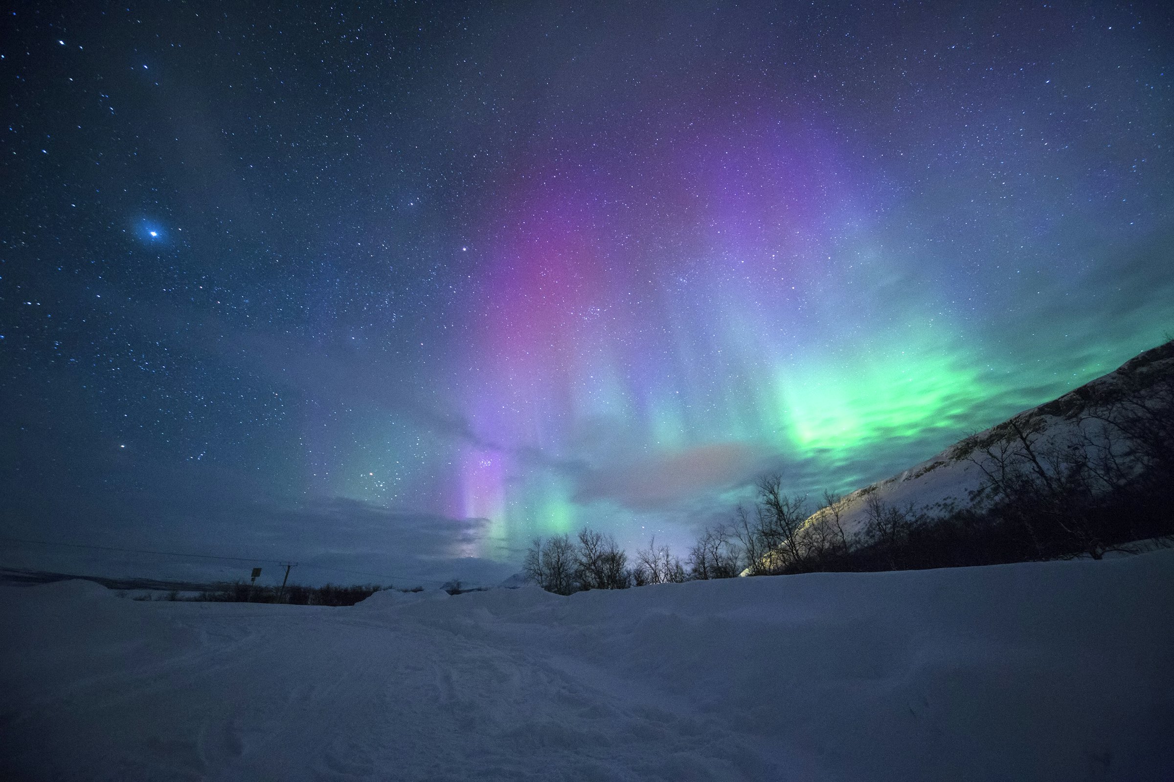 Aurora boreal sobre montanhas nevadas perto de Tromsø, na Noruega